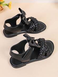 1 par de sandalias planas de color negro para niñas y niños de talla grande, de 3 a 15 años, con decoración de lazo grande tejido de unicolor, cierre con correa, punta redonda y abierta, sandalias romanas de moda y lindas, adecuadas para uso casual, fiesta, viaje, primavera/verano 2025