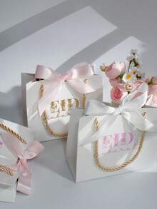 5个优雅的开斋节礼品袋，配粉色和白色缎带，奢华白色纸质礼品袋，金色绳柄，适用于糖果、椰枣、珠宝、小礼物和派对回礼，是开斋节庆祝活动、斋月礼品包装、家庭聚会、清真寺活动、课堂交换、伴娘回礼、婴儿派对和节日礼品包装的理想之选。 - 14X6X12cm - 查看 1