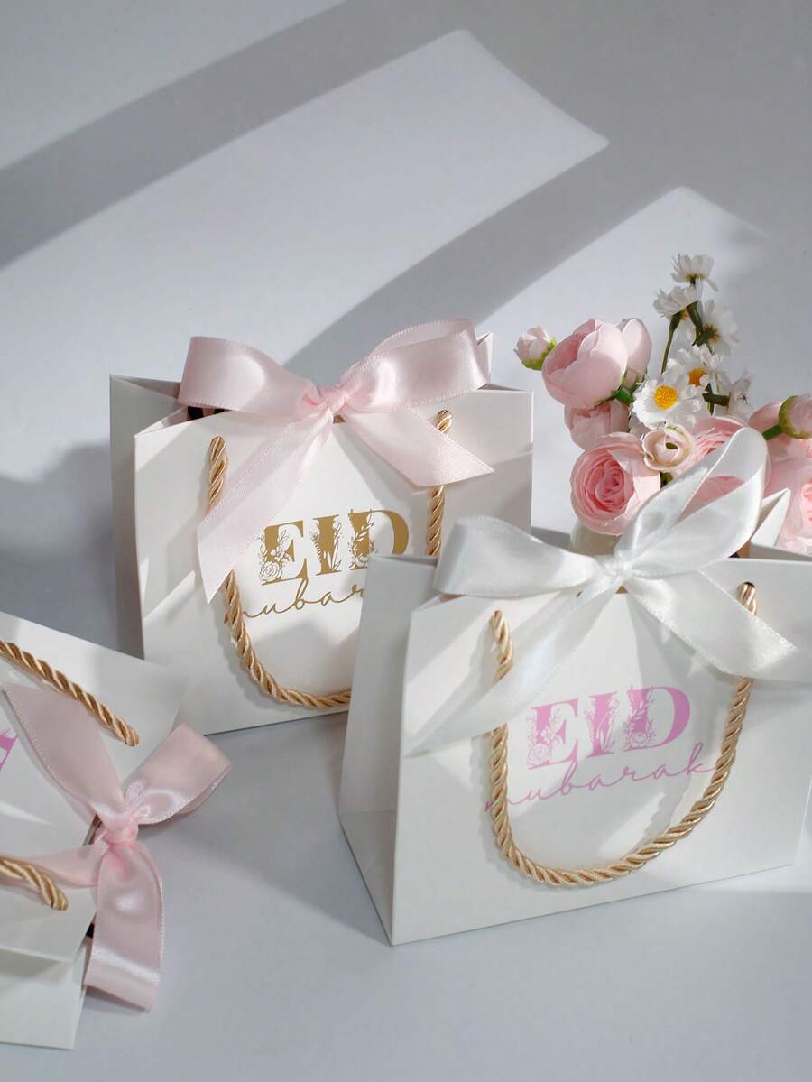 5个优雅的开斋节礼品袋，配粉色和白色缎带，奢华白色纸质礼品袋，金色绳柄，适用于糖果、椰枣、珠宝、小礼物和派对回礼，是开斋节庆祝活动、斋月礼品包装、家庭聚会、清真寺活动、课堂交换、伴娘回礼、婴儿派对和节日礼品包装的理想之选。 - 14X6X12cm - 查看 1