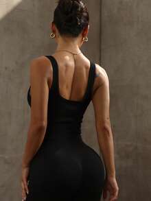 Women's Minimalist Black Cross-Back Yoga Jumpsuit With Flared Legs. Perfect For Indoor And Outdoor Practice, Designed For A Confident And Elegant Stride.