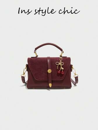 Este es un bolso de mujer de color borgoña con un dije de cereza roja, versátil y elegante, con cierre de botón magnético, cremallera interna suave, correa de hombro ajustable y espacio interior para artículos de uso diario como lápiz labial, llaves y cosméticos, adecuado para ir al trabajo, de compras, citas y salidas diarias.