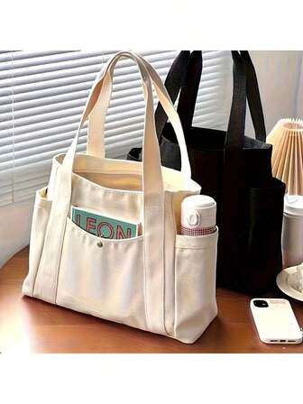 1个黑白超大容量帆布手提袋，简约时尚，适合通勤、上学、旅行，可装学习用品，外部口袋可放置水瓶和手机。