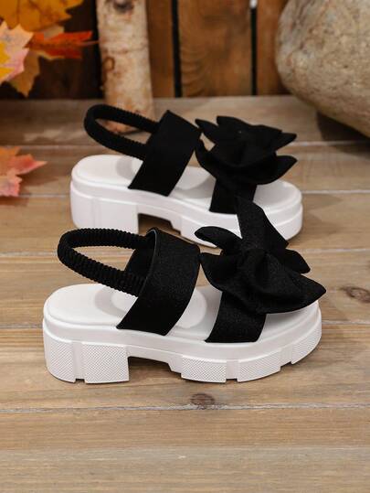 1双黑色坡跟凉鞋，大童款，柔软面料，蝴蝶结装饰，弹性后跟带，圆头设计，3厘米厚防滑鞋底，可爱时尚，适合海滩/休闲/上学/度假穿着，春夏皆宜。