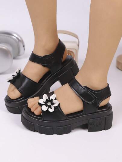 这款柔软厚底女童凉鞋饰有花朵装饰的鞋带，时尚的夏季款式，适合 3 至 15 岁的儿童在户外玩耍和海滩上穿着。