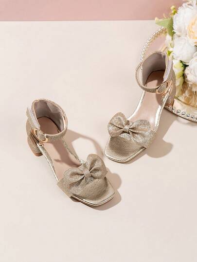 1 par de sandalias decoradas con lazo dorado para niñas, con parte superior de piel sintética artificial y un brillante lazo rosa y correa para el tobillo que se ajusta a los pies. El estilo de puntera cuadrada y parte superior baja es cómodo con un tacón bajo, brillando con una brisa dulce, adecuado para celebraciones de vacaciones y ocasiones de estilismo de niña de las flores.