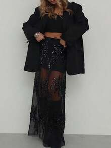 Saia preta de lantejoulas, elegante e com recortes em tule, ideal para festas e encontros românticos no início da primavera.