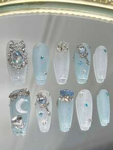 Bộ 10 móng giả hình quan tài dài, màu xanh dương lấp lánh, phong cách "Tinh khiết và quyến rũ". Móng giả dán phủ toàn bộ được trang trí bằng nơ đính đá, vòng hoa, đá hình trăng khuyết, đũa phép, đá hình trái tim và đá hình "trứng" màu xanh dương (thuật ngữ chỉ những viên đá lớn, bắt mắt) xếp chồng lên nhau. Dụng cụ làm móng, móng giả dán thủ công. - Nhiều màu - Xem 11
