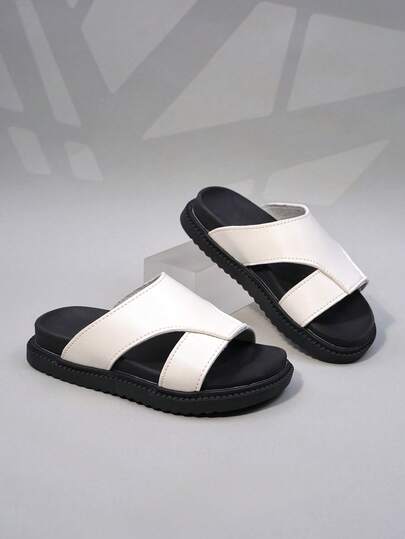 1双黑白撞色交叉绑带女童拖鞋，采用合成革材质，交叉绑带设计穿着舒适，露趾低帮，厚底平底，简约休闲风格，适合日常上学或户外活动。