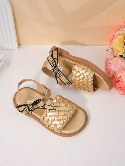 1 Pair Of Girls' Shoes With Golden Woven Ribbon Bow Sandals, The Upper Is Made Of Faux Leather Woven Material, The Woven Ribbon+Letter Bow Decoration, The Back Strap Adjusts The Elasticity, The Open Toe Low Top Style, Thick Sole Flat Heel, Retro Princess Style, Suitable For Birthday Parties And Children's Dance Party Styling