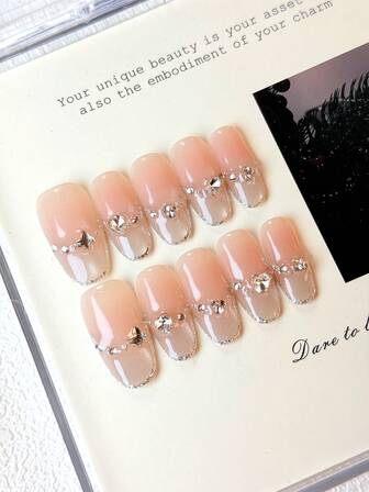 10 st. ovala press-on naglar med nakenrosa gradient, transparent glitterton, mjukt utsökt bas, silverfärgad strassdekor, stjärn- och hjärtformade accenter och silverfärgade kantelement. Glansiga 100 % handgjorda press-on akrylnaglar. Återanvändbara nageltillbehör inklusive 1 st. gelélim, 1 st. stift och 1 st. nagelfil för kvinnors vardags- eller festkläder.