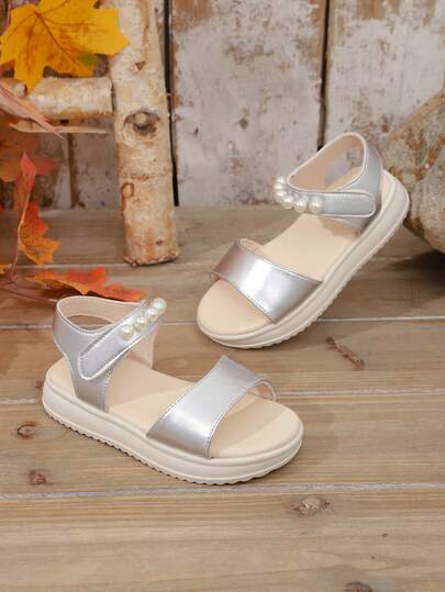 A Pair Of The Latest Silver Pearlescent Faux Pearl Strap Hook And Loop Sandals For Children In Summer - A Comfortable Style, An Excellent Choice For Daily Outings, Shopping In Malls, And Summer Vacations.