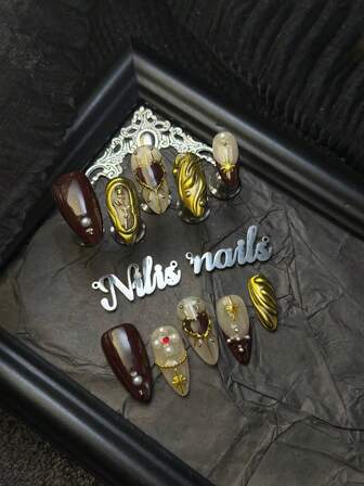 10片装手工美甲套装，杏仁形酒红色和金色美甲贴片，搭配酒红色法式点缀，朋克摇滚金属质感3D装饰，春夏美甲套装，手绘爱心，3D玫瑰图案，适合女孩日常佩戴，也适合参加聚会、主题派对和其他活动。套装包含1个迷你指甲锉和1张双面胶标签。