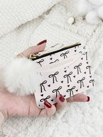 这款带绒球挂饰、蝴蝶结爱心图案的拉链小钱包，配有零钱袋，纤薄轻巧，多层设计，可装身份证、现金、信用卡等，简约时尚，适合商务场合，是周年纪念、生日、送礼的理想之选，也适合送给女孩、女士或女性，是学校宿舍和返校季的必备单品。