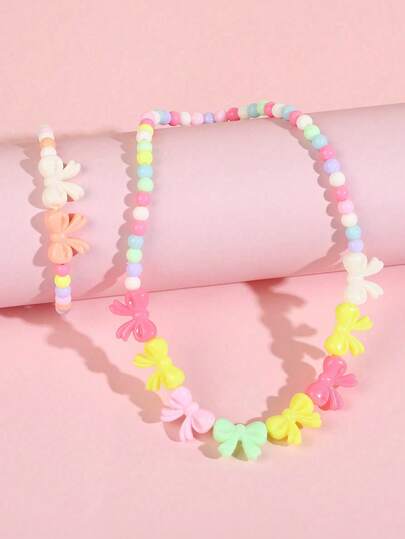 Bộ trang sức 2 món cho bé gái gồm mặt dây chuyền hình nơ dễ thương và vòng tay đính hạt, thích hợp cho các lễ hội, tiệc tùng, sinh nhật và đeo hàng ngày (màu hạt ngẫu nhiên).