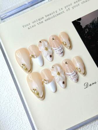 10 piezas de uñas postizas ovaladas de longitud media-larga con degradado rosa nude y blanco, con decoración de flores 3D (con acentos de oro y rhinestone), diseño a cuadros, elementos de perlas y rhinestones pequeños y diseño de bordes dorados brillantes. Incluye 1 pieza de pegamento de gelatina, 1 pieza de palito y 1 pieza de lima de uñas para uso diario o de fiesta de mujeres.