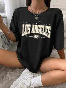 Camiseta de manga corta informal para niña - Estampado gráfico Los Angeles 99, cuello redondo, tejido de punto, color negro con letras amarillas, corte regular, lavable a máquina, cómoda para todas las estaciones, ideal para actividades al aire  uso casual, tejido ligeramente elástico. - Negro - Ver 1
