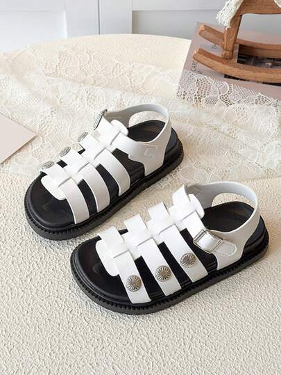 一双女童黑白撞色金属扣罗马凉鞋，鞋面采用人造革材质，饰以金属花朵扣，低帮露趾设计，舒适厚底，休闲风格，适合日常上学和户外玩耍。
