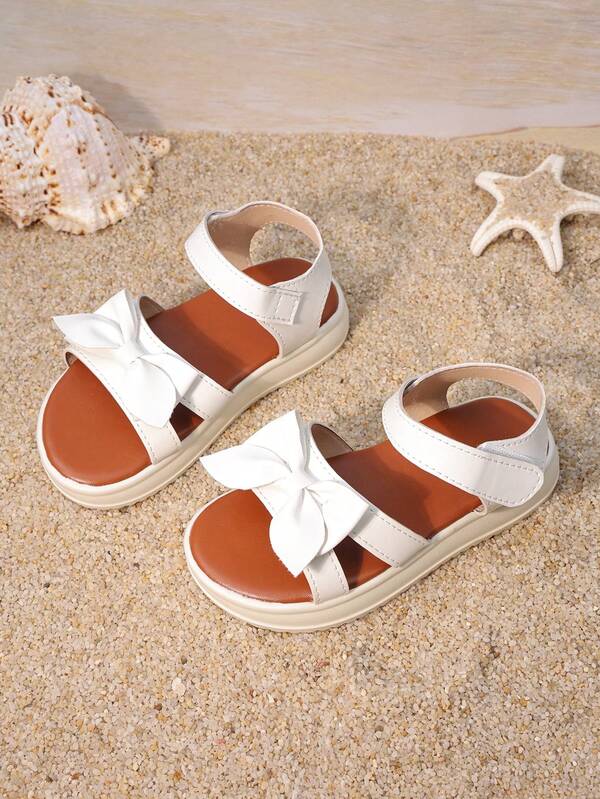 一双女童白色蝴蝶结厚底凉鞋，鞋面采用人造革材质，饰有立体蝴蝶结，低帮露趾设计，厚底防滑，甜美风格，适合日常上学和户外花园活动。