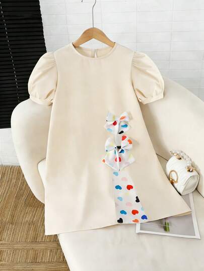 Đầm ngắn tay phồng 3D thoải mái cho bé gái đi nghỉ mát, họa tiết trái tim nhiều màu sắc, phối ghép, điểm nhấn nơ lớn, dáng chữ A rộng rãi, thích hợp mặc hàng ngày khi đi nghỉ mát.