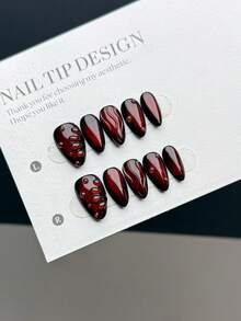10片纯手工制作的可佩戴美甲贴片，短款杏仁形，采用按压式设计，风格简约奢华，饰以深黑红色猫眼效果，并点缀手工绘制的透明水滴线条图案。这是一款高端美甲贴片，适合女性和女孩日常佩戴，套装包含10片美甲贴片。美甲用品 手工按压式美甲贴片 - 彩色 - 查看 4