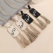 一件木制工艺装饰品，饰有阿拉伯字母图案、木珠和黑白流苏绳，适合家居装饰，可用作橱柜/抽屉拉手，也适用于咖啡馆和茶馆的花瓶装饰，是房间和墙面装饰的理想之选。