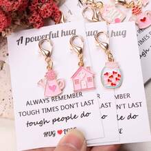 8件套心形主题励志鼓励口袋拥抱礼盒：包含“充满力量的拥抱”卡片，以及独特的粉色吊坠钥匙扣、台灯、茶壶、许愿瓶、漂流瓶、花束和爱心小屋等装饰配件。适合情侣、家庭、生日、节日派对、情人节和母亲节等场合作为礼物。