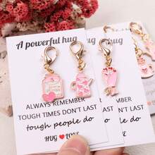 8件套心形主题励志鼓励口袋拥抱礼盒：包含“充满力量的拥抱”卡片，以及独特的粉色吊坠钥匙扣、台灯、茶壶、许愿瓶、漂流瓶、花束和爱心小屋等装饰配件。适合情侣、家庭、生日、节日派对、情人节和母亲节等场合作为礼物。