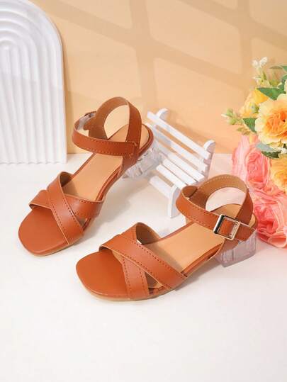 1双女童棕色鞋底仿皮交叉绑带凉鞋，仿皮鞋面，后跟绑带固定，交叉绑带+露趾款式，低跟舒适，百搭甜美又酷炫的女童鞋，适合派对装扮和闺蜜聚会。
