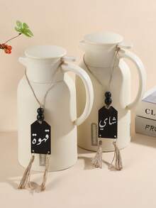 一件木制工艺装饰品，饰有阿拉伯字母图案、木珠和黑白流苏绳，适合家居装饰，可用作橱柜/抽屉拉手，也适用于咖啡馆和茶馆的花瓶装饰，是房间和墙面装饰的理想之选。