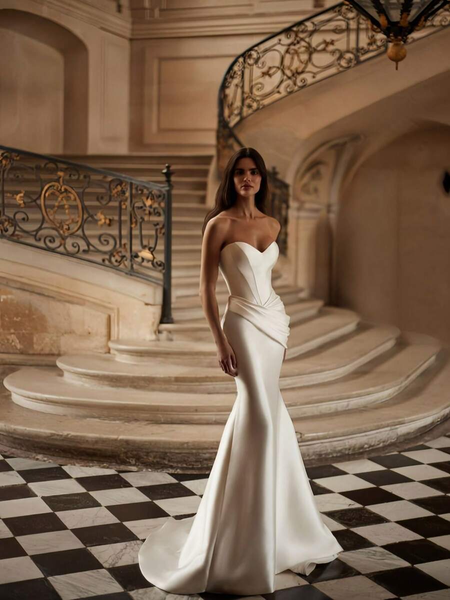 Sophisticated Strapless Mermaid Wedding Dress with Sweetheart Neckline and Open Back – Elegant Floor-Length Ivory Bridal Gown Featuring a Sculpted Silhouette that Flares into a Dramatic Skirt, Accented by a Daring Low-Back Design. This Gown Combines a Timeless Bustier with a Captivating Mermaid Cut, Creating an Enchanting Look for Special Moments. Perfect for Weddings, Holiday Galas, Christmas Celebrations, Halloween Parties, Prom Nights, and Grand Occasions. A Stunning Formal Gown Ideal for Bridal Ceremonies, Receptions, Festive Events, Formal Dinners, Graduation Balls, and Cherished Celebrations. - Blanco - Ver 1