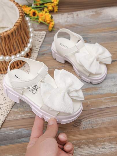 Giày sandal nơ to mới cho bé gái mùa xuân và hè, đế xốp dày chống trượt, hở mũi, kiểu La Mã.