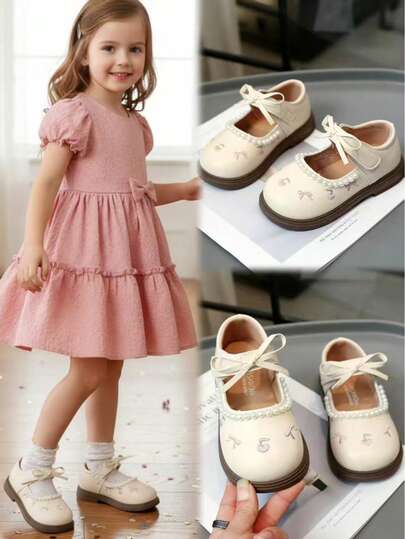 1双米色轻便透气休闲平底鞋，适合幼儿和小女孩穿着。鞋面采用简约优质的PU材质，饰以水果刺绣、蝴蝶结和珍珠吊坠，洛丽塔风格，舒适的弹性内衬，耐磨厚橡胶鞋底，魔术贴设计，适合搭配公主裙、日常穿着、上学、外出、派对、度假等场合，2026春夏款。
