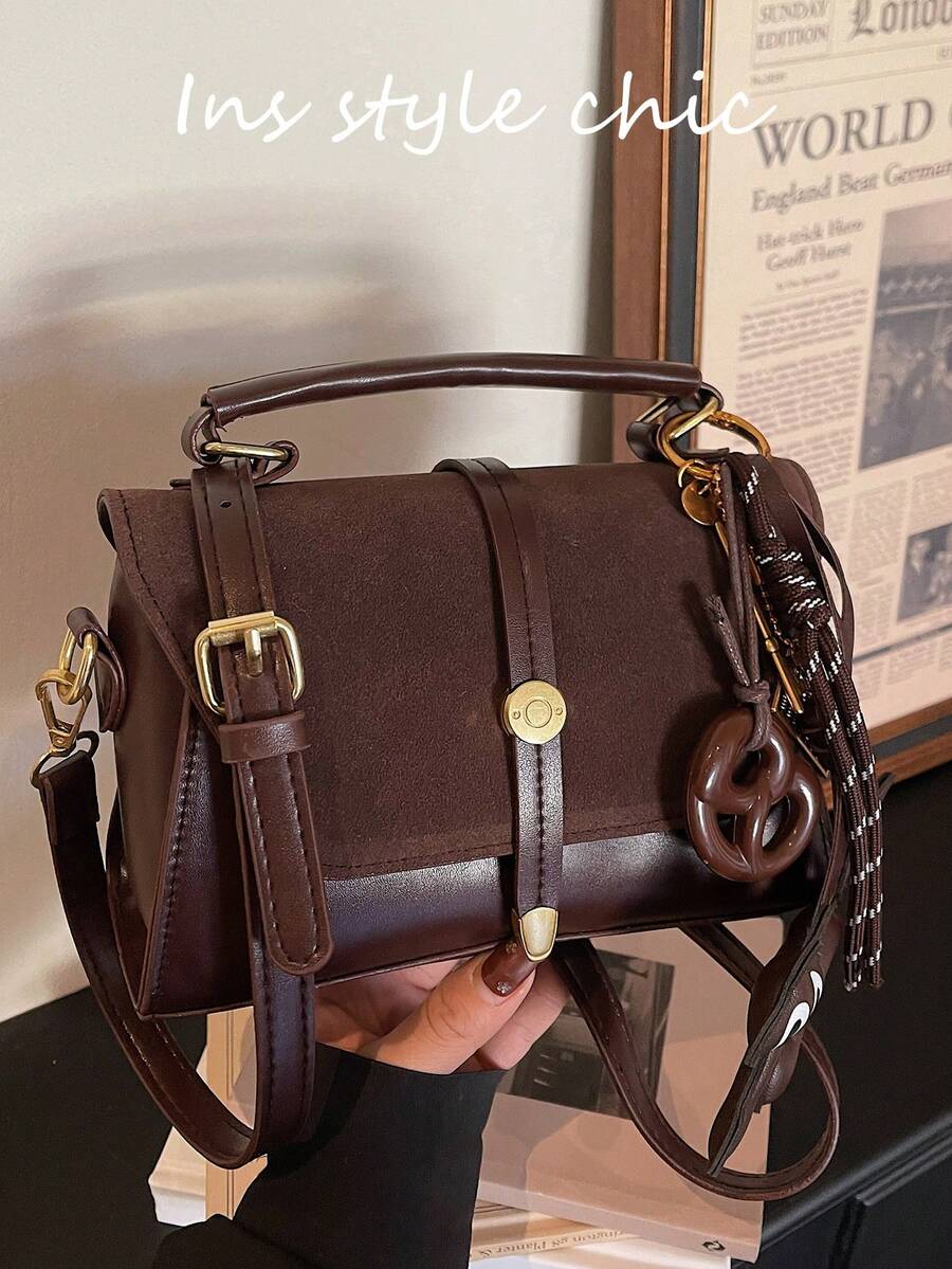 这款全新时尚经典方形手提包采用金属搭扣、可调节肩带、麂皮材质和翻盖设计，并饰有猫咪饼干吊坠。非常适合户外活动、通勤、购物、学校旅行和短途度假。