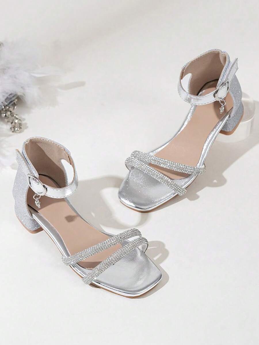 一双儿童闪亮水钻高跟凉鞋，采用时尚T字带设计，鞋面镶嵌水钻，优雅的踝带和吊坠装饰，粗跟设计确保行走稳定。适合小女孩在婚礼、派对或生日等正式场合穿着，每一步都闪耀夺目，成为众人瞩目的焦点。 - 銀色 - 查看 1