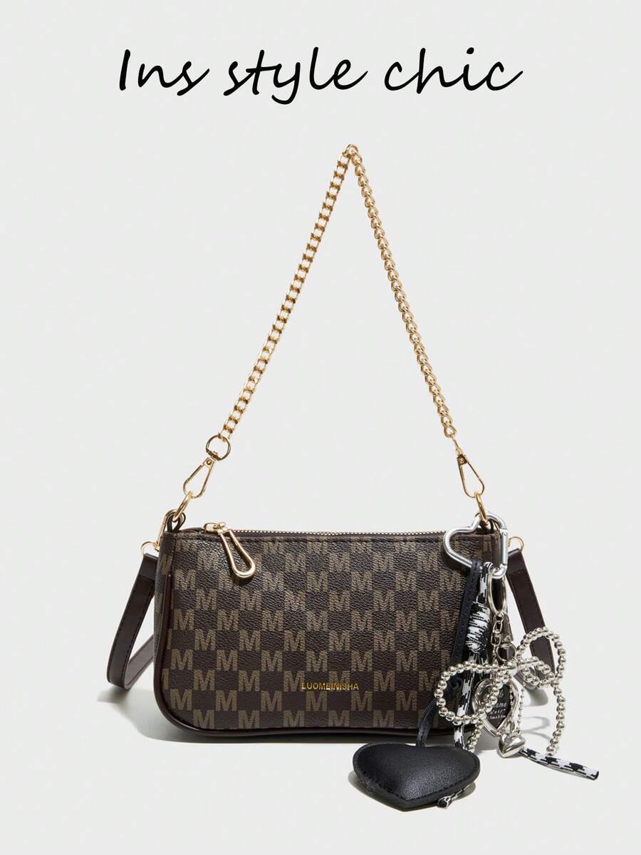 这款全新时尚经典单肩包采用防水PU材质，饰有M形印花、金属链条和黑色心形吊坠。这款法式手提/单肩包是购物的理想之选。