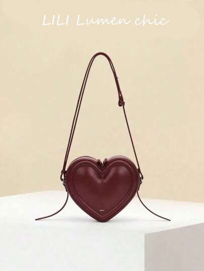 心形单肩包设计，立体心形包身，女士单肩斜挎两用包，多功能手提包，饰有字母Logo，纯色PU材质，顶部单提手，可调节肩带，五金拉链封口，可单肩、手提或斜挎。