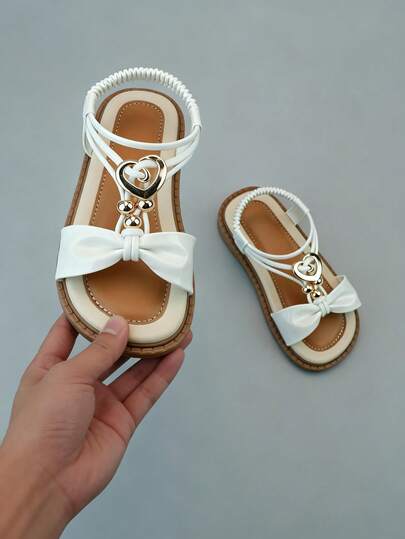 This Children's Sandal Is Suitable For Girls Aged 4 To 8 Years Old. It Features A Princess White Main Color Tone, Paired With A Light Brown Sole, Bow, And Heart-Shaped Metal Buckle. The Elastic Ankle Strap Makes It Easy To Put On And Take Off. The Wavy Sole Provides Anti-Slip And Non-Chafing Material.