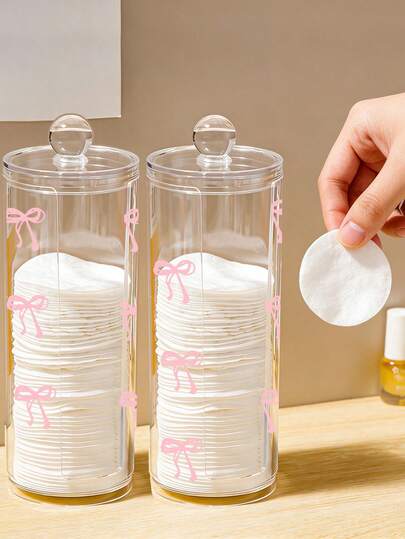 صندوق تخزين شفاف دائري مع تصميم فيونكة وردية، سعة كبيرة، قابل للغسيل وسهل التنظيف. مناسب لتخزين وسادات القطن وشرائط الجفن وإسفنجات المكياج وإسفنجات التنظيف وأدوات التجميل الصغيرة الأخرى. منظم مكتبي.