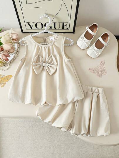 Bộ 2 món cho bé gái: Áo không tay cổ nơ màu trơn và quần họa tiết bí ngô màu trơn, thích hợp cho mùa hè.