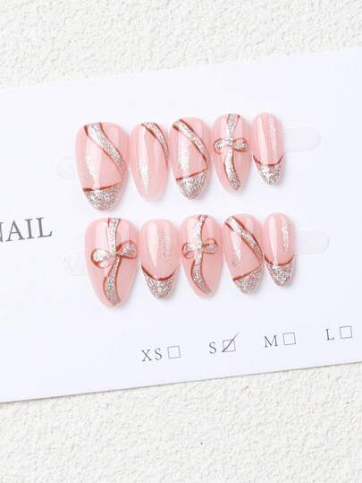 10片手工制作的杏仁形浅粉色银色闪粉全覆盖假指甲，饰以手绘蝴蝶结，时尚精致。它们为您的指尖增添浪漫气息，同时大胆展现您的时尚品味。非常适合派对、晚宴和日常佩戴，也是送给女性和女孩的绝佳礼物。尤其适合新年和情人节。