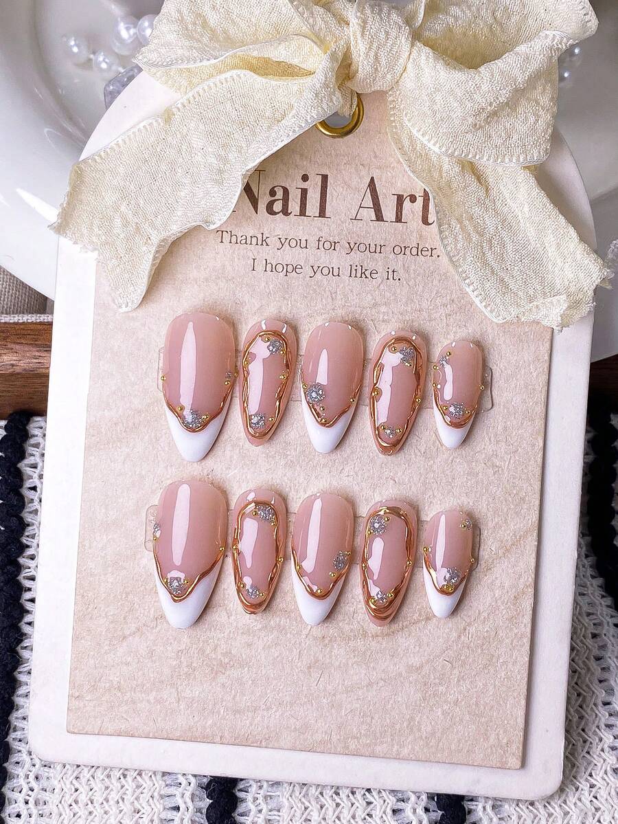 10片手工制作杏仁形白色不对称法式美甲贴纸，饰以银色水钻和金属线条。这些杏仁形美甲贴纸均为纯手工制作，展现独特的白色不对称法式甲尖，并以手绘金属线条勾勒轮廓，点缀以闪亮的银色水钻。美甲用品 - 彩色 - 查看 1