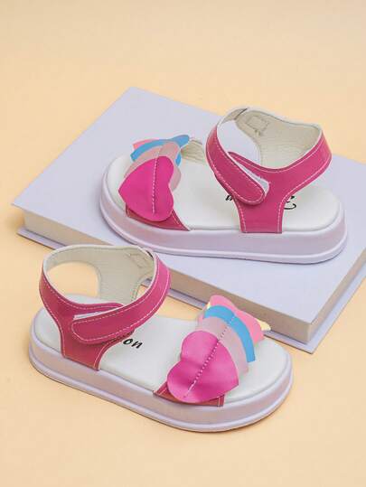 可爱童鞋！这款适合4-8岁女孩的撞色心形漆皮凉鞋，采用亮粉色主色调和厚实的华夫格鞋底。可调节的鞋带方便穿脱。防滑鞋底和漆皮材质易于清洁。充满柔软、可爱、甜美的元素，适合日常穿着。
