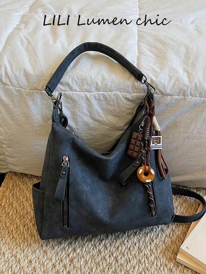 这款时尚经典的大容量单肩包采用竖向拉链设计，饰有装饰吊坠，并配有顶部提手。这款百搭的女士单肩包适合各种场合，包括通勤、工作、旅行、聚会和购物。