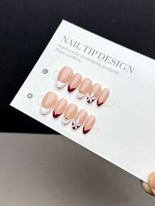 10片纯手工制作的可佩戴美甲贴片，短款杏仁形，按压式设计，时尚简约。饰有手绘红白法式美甲图案，搭配金色太阳纹和白色洋紫荆花纹。这款高端美甲贴片适合女士和女孩日常佩戴，并配有美甲套装。美甲用品 - 彩色 - 查看 1
