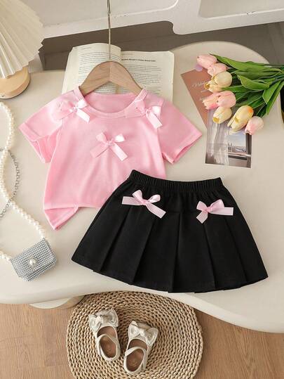 Conjunto de ropa de verano adorable para niñas pequeñas, conjunto informal de camiseta de verano para bebés niñas con decoración de lazo, blusa de manga corta de cuello redondo rosa y falda plisada negra, conjunto de 2 piezas