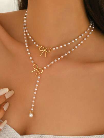 浪漫甜美的女士金属首饰两件套，包括一条饰有蝴蝶结的锁骨链和一条百搭的仿珍珠流苏项链。时尚百搭，既可单独佩戴，也可叠戴。