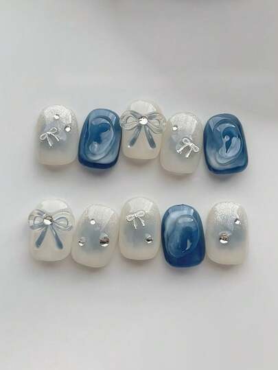 10 pièces Ongles courts ovales bleus et blancs purs faits à la main. Ongles français élégants de style dégradé bleu et blanc avec nœud papillon tridimensionnel et ornement de diamant écrasé. Ongles simples et doux à clipser, idéaux pour les femmes et les filles, à porter au printemps, en été, en automne, en hiver, lors de festivals, de fêtes et dans la vie quotidienne.