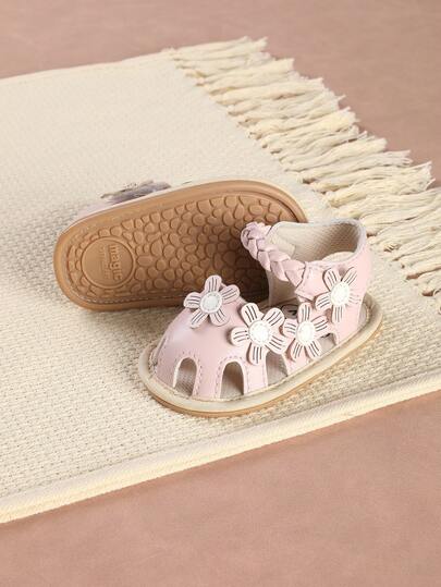 Ett par flickskor med kardborrestängning, söta blommiga platta sandaler lämpliga för sommaren