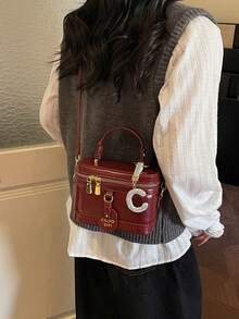 这款女士纯色PU皮手提包，酒红色调，设计时尚百搭，外部饰有水钻C形吊坠。包身呈方形，配有字母标签、顶部光滑的金属拉链和单提手。可调节长肩带方便肩背。 - 酒紅色 - 查看 6