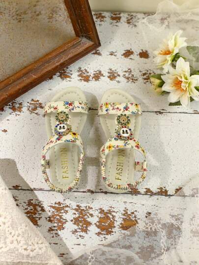 1 đôi dép xăng đan đế bằng quai chữ T cho bé gái, trang trí họa tiết hoa và có quai hậu co giãn.